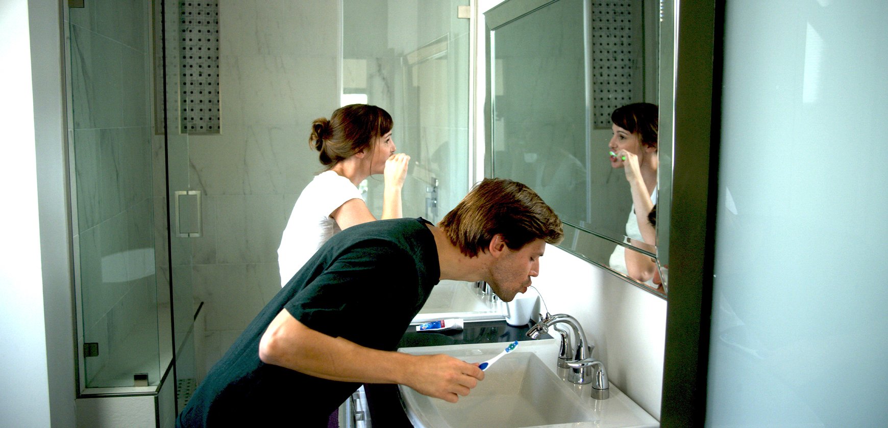 Young couple brushing teeth in modern bathroom with Nasoni faucets